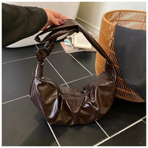 Detailed close-up of dark brown pleated cloud bag with stylish knotted shoulder strap