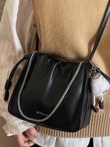 Sac à bandoulière noir froncé avec chaîne argentée et pendentif peluche sur beige