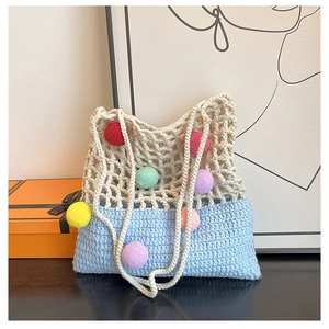 Detail of knit crochet tote bag with colorful pom-poms and mixed stitching patterns