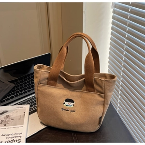 Gros plan du sac à main en toile avec broderie cartoon et poignée solide