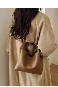 Vista de modelo de un bolso bowling color caramelo con una gabardina color caqui