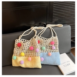 Close-up of handmade knit tote bags featuring vibrant colorful pom-poms on woven texture