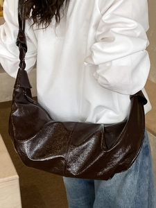 Dark brown glossy crescent bag with ruched design and knotted strap, crossbody style