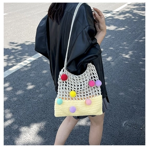 Close-up of knit tote bag featuring colorful 3D pom-poms and textured mesh weave detail