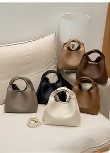 Bolsos tipo cubo con textura de lichi en seis colores sobre sofá blanco con correas