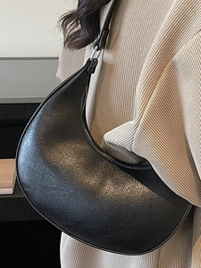 Minimalist black crescent moon underarm bag with grainy leather texture and silver buckle