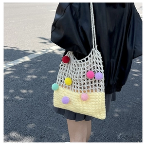 Detail of hand-knitted tote bag with macaron pom-poms and cream hollow mesh design