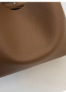 Primer plano de la textura de cuero lichi marrón y detalle de hebilla metálica del bolso
