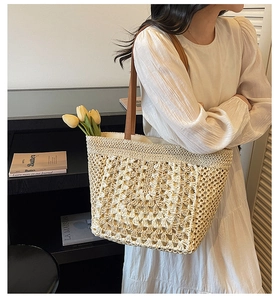 Detail of hand-woven straw tote with diamond crochet pattern and brown leather strap