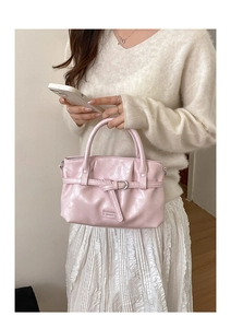 Detailed close-up of a pink patent leather handbag with fashion metal buckle and round handle