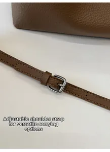 Detalle de la correa ajustable de cuero marrón con hebilla de metal plateado y costuras