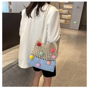 Detail of handmade crochet shoulder bag with colorful pompoms and blue beige mesh texture