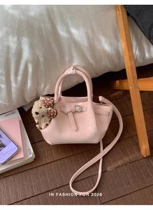Pink bucket bag with a cute teddy bear charm and soft bow on dark wood floor