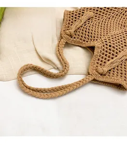Détail du sac cabas tissé avec poignées tressées et décorations de glands latéraux