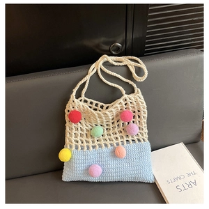 Close-up of a handmade knit tote bag with colorful pom-poms and crochet mesh details