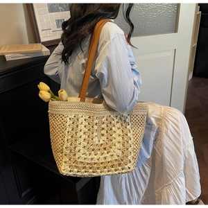 Detail of French style hand-woven straw tote with beige floral crochet pattern and brown straps