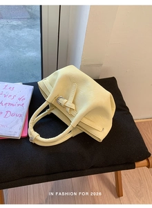 Detailed view of pale yellow bucket bag with wrinkled texture and silver buckle accents