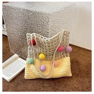 Detail of hand-knitted tote bag with colorful pom-poms and mixed weaving texture