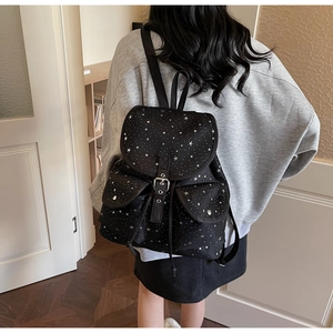 Détail d'un sac à dos en toile noire à imprimé étoiles et doubles poches avant sur mannequin