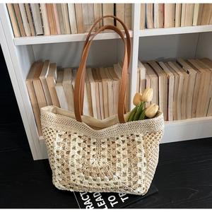 Detailed close-up of woven straw tote bag with brown leather strap and hollow-out texture