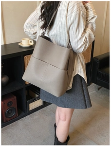 Close-up of taupe litchi grain leather bucket bag with wide shoulder strap details