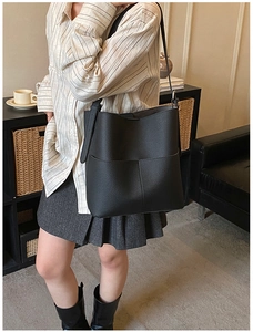 Detail of black lychee leather bucket bag with stitching pocket shown on a model
