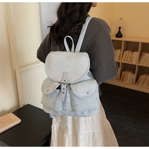 Détail du sac à dos en toile bleu clair avec étoiles argentées et deux poches avant