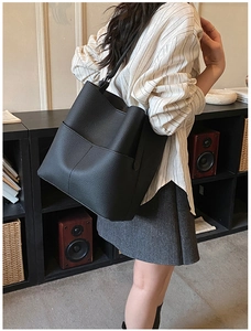 Close-up of the black lychee texture leather bucket bag worn over the shoulder