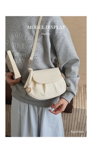 Sac bandoulière crème chic avec boucle anneau doré porté par un mannequin