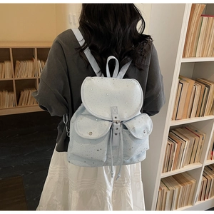 Détail du sac à dos bleu clair avec motifs d'étoiles et boucles de poche sur le devant