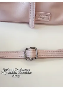 Detailed view of pink leather bag featuring logo embossing and silver metal adjustment buckle
