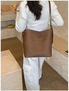 Detailed view of the dark brown lychee leather texture and white stitching on bucket bag