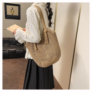 Détail du sac tricoté main kaki avec motif ajouré en maille et pompon décoratif élégant
