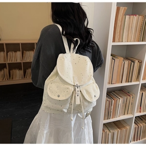 Vue détaillée d'un sac à dos en toile crème avec motif étoile argenté et boucle