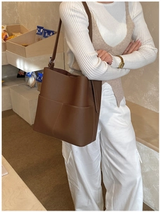 Detail view of large brown vintage bucket bag worn by model in a cozy lifestyle setting
