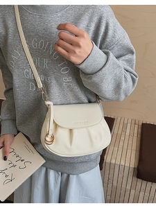 Détail du sac bandoulière plissé crème avec anneau doré élégant et lettrage de mode