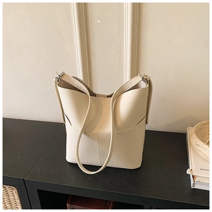 Macro detail of creamy leather texture and silver buckle on bucket shoulder bag