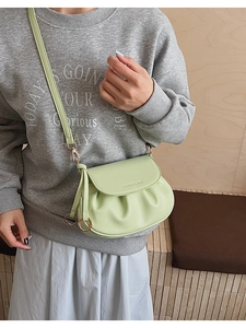 Détail d'un sac bandoulière vert clair avec design plissé et anneaux dorés élégants