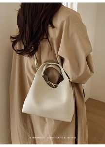 Bolso bowling crema elegante con textura de lichi usado como bandolera sobre gabardina