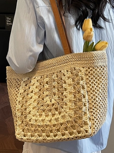 Handwoven straw tote bag with brown leather strap and hollow crochet texture for summer beach