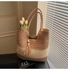 Detail of hand-woven straw tote with brown stripes, tassels, and wooden beads