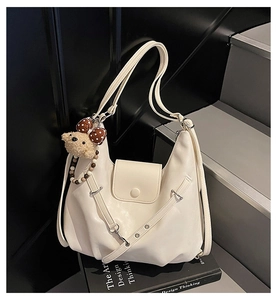 Detailed close-up of cream crescent tote bag with soft leather texture and bear charm