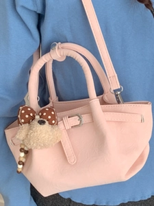 Pink bucket handbag with plush poodle charm shown as a cross-body bag for women