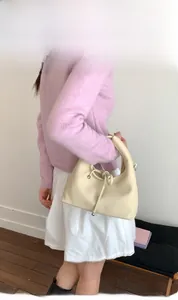 Detail of off-white lychee grain leather bag with unique metal bead drawstring knot