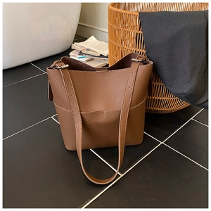 Close-up of brown litchi grain leather bucket bag with detailed stitching and shoulder strap