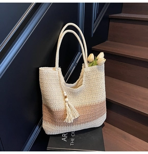 Close-up of woven straw tote bag with gradient texture and boho tassel detail