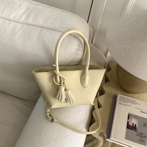 Détail d'un sac seau crème minimaliste avec pompons en cuir dans un salon chic et moderne