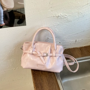 Detailed close-up of light pink bucket bag with buckle straps and glossy PU leather texture