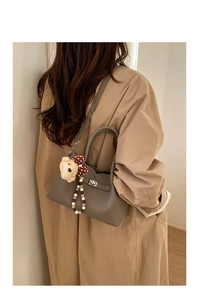 Détail du sac seau en cuir taupe avec fermoir argenté et breloque ourson mignon