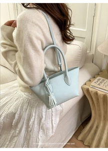 Vue détaillée du sac seau bleu menthe minimaliste avec pompon sur un canapé